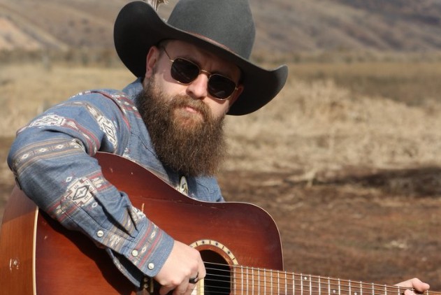 Skylar Geer holding a guitar outside. 